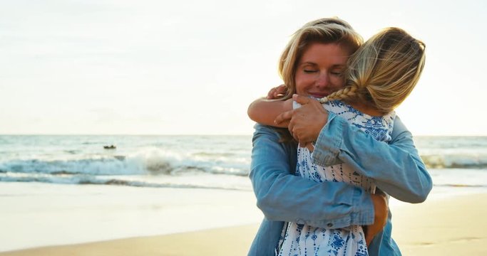 Mother and daughter having fun playing on the beach at sunset