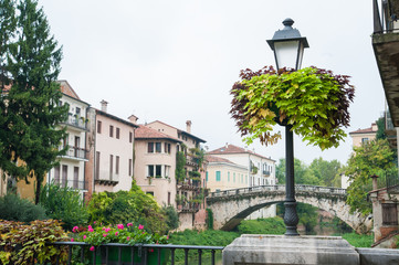 Flowered street lamp along Saint Paul bridge in Vicenza, Saint Michele bridge in the background