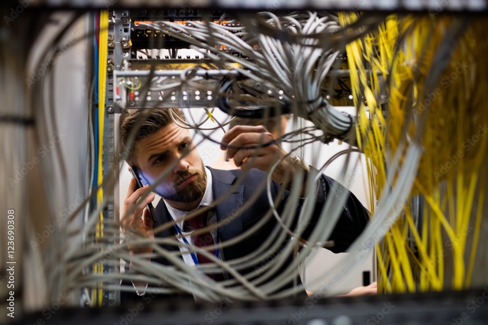 Poster technician talking on mobile phone while checking cables