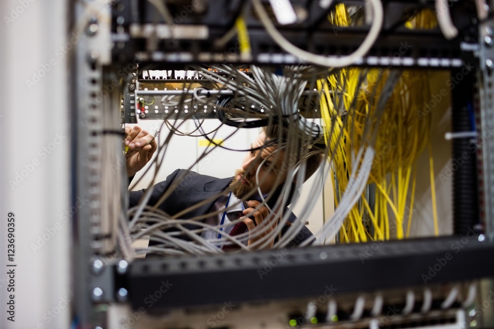 Poster technician talking on mobile phone while checking cables