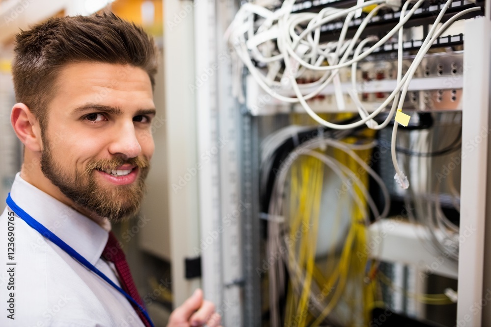 Poster smiling technician standing in a server room