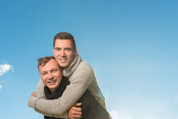 Two young men smiling and holding one another.