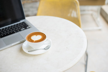 Laptop and coffee cup on wooden table