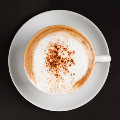 Hot cappuccino with cinnamon in a white cup.