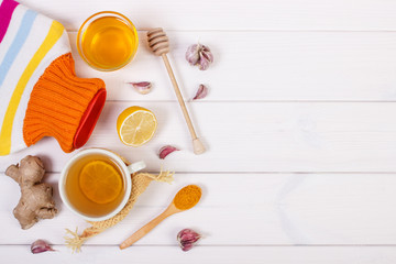 Hot water bottle, cup of tea and ingredients for preparation warming beverage, copy space for text