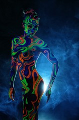 Slim woman posing nude with luminous body art