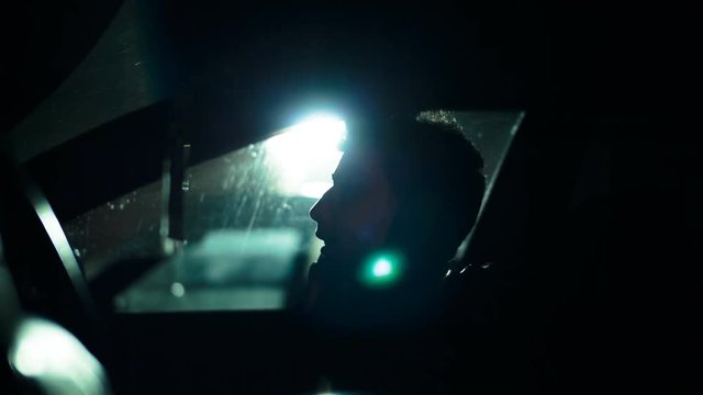 Profile of a man in a car on a dark night. Noir style