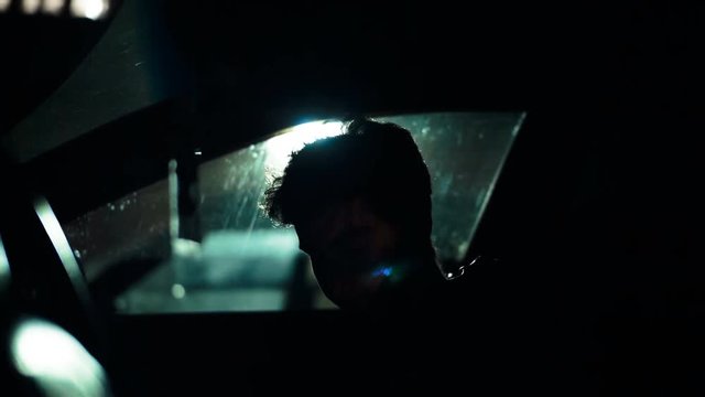 Profile of a man in a car on a dark night. Noir style