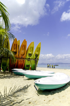 colorful stacking kayaks on white sandy beach at sunny day. blue sky and clear sea water background.image taken at Kapas Island (Cotton Island), Malaysia