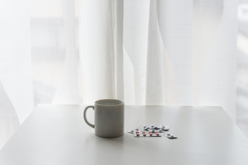 white pills lying next to a glass of water on a wooden table
