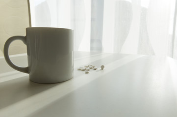 white pills lying next to a glass of water on a wooden table
