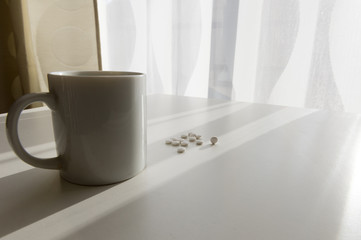 white pills lying next to a glass of water on a wooden table
