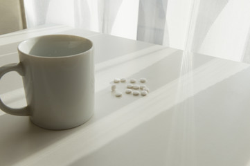 white pills lying next to a glass of water on a wooden table
