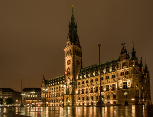 Fototapeta na wymiar golden leuchtendes Hamburger Rathaus bei Nacht mit Spiegelung auf nassem Rathausplatz