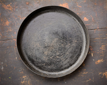 Old Cast Iron Frying Pan On The Black Wooden Table Close-Up Top View