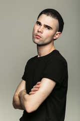 Man looking at camera with hands crossed against grey background