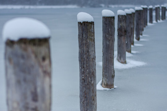 Schneebedeckte Holzpf&auml;hle in zugefrorenem See