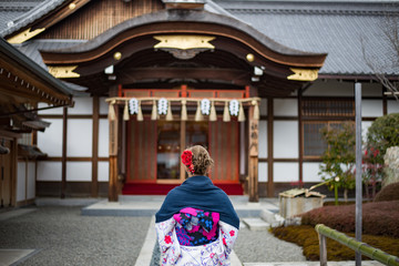 Woman dressed in traditional japanese costume walking under tori