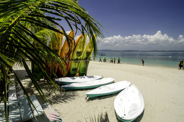 colorful stacking kayaks on white sandy beach at sunny day. blue sky and clear sea water background.image taken at Kapas Island (Cotton Island), Malaysia