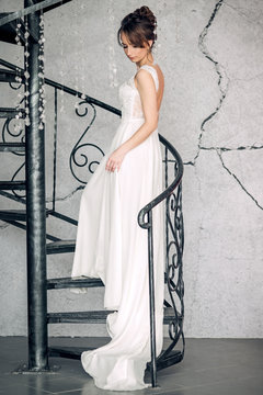 Beautiful young bride standing on a forged stairs in a bright interior