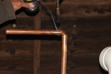 Plumber soldering a copper gas pipe to a boiler