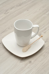 A white mug and saucer displayed with a sugar stick