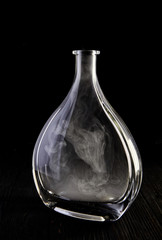 Empty decanter with smoke on black background