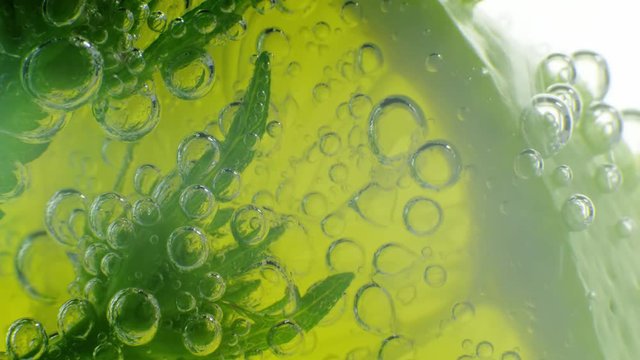 Sparkling bubbles water with a slice of lime. Slow motion macro footage.
