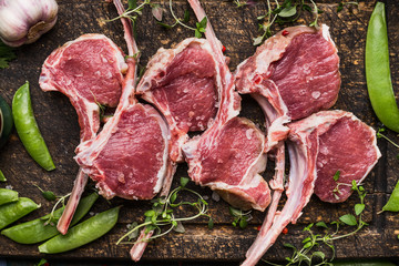 Raw meat  rack of lamb  and green pea on dark wooden background, top view, close up