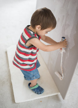Little cute boy painting on a wall
