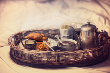Breakfast in bed on a tray: vintage coffee pot, Cup of coffee and croissants, selective focus