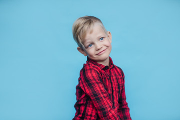 Handsome little boy with red shirt. Fashion. Studio portrait over blue background