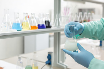 Hands in latex gloves holding flasks in the laboratory