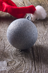 silver Christmas ball on a wooden background with a red cap
