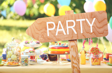 Word PARTY on wooden signboard against blurred festive background
