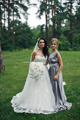 Fototapeta na wymiar The tenderness bride with bridesmaid in the park