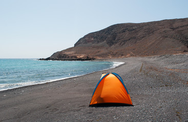 Fuerteventura, Isole Canarie: una tenda arancione sulla spiaggia nera di Pozo Negro, piccolo...
