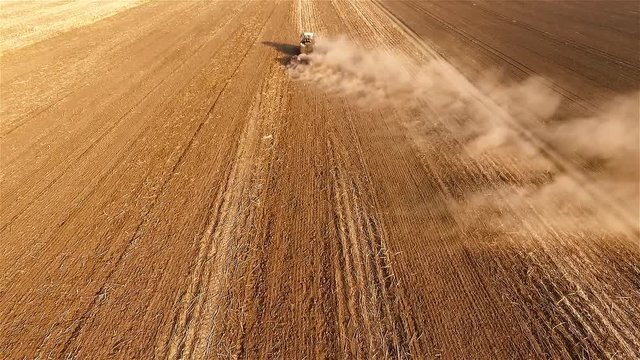 Cultivation soil: flight over farm tractor plowing on cropped field after harvesting HD aerial video. Agricultural machine equipment. Preparation for sowing seed