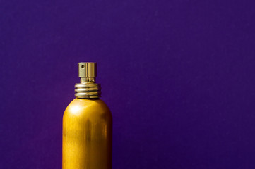 One golden bottle of perfume on purple background. Cosmetic spray
