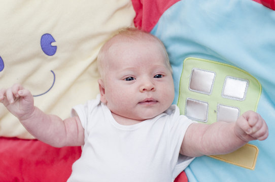 Cute newborn baby playing on a playmat baby play gym