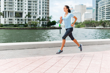 Fototapeta na wymiar Young woman running jogging near water in downtown Miami