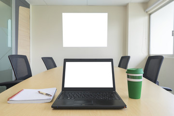 laptop  display picture on wall with notebook and cup of coffee on table in meeting room