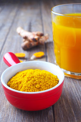 Close up of immunity-boosting spicy turmeric power and tea on a wooden table.