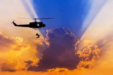 Zelfklevend Fotobehang    silhouette soldiers in action rappelling climb down from helicopter with military mission counter terrorism assault training on sunset  © Soonthorn