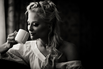 Black and white picture of a pretty blonde while she drinks a co
