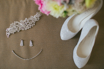 Bride's jewellery lied in a form of smile lie on the floor behin
