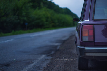 Car on the side of the road on a cloudy day near the forest