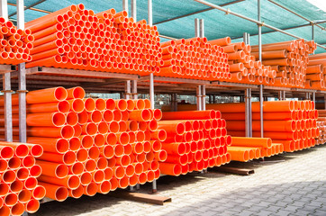 Stack of orange pvc water pipes in abandoned industrial area