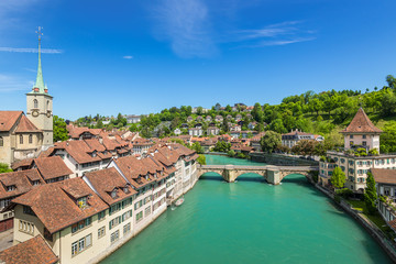 Fototapeta na wymiar A wide-angle view of the Aare River, Сhurch, bridge and houses with tiled rooftops at Bern, Switzerland