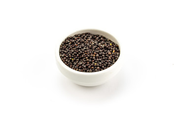 Mustard seeds in little bowl closeup isolated on white background